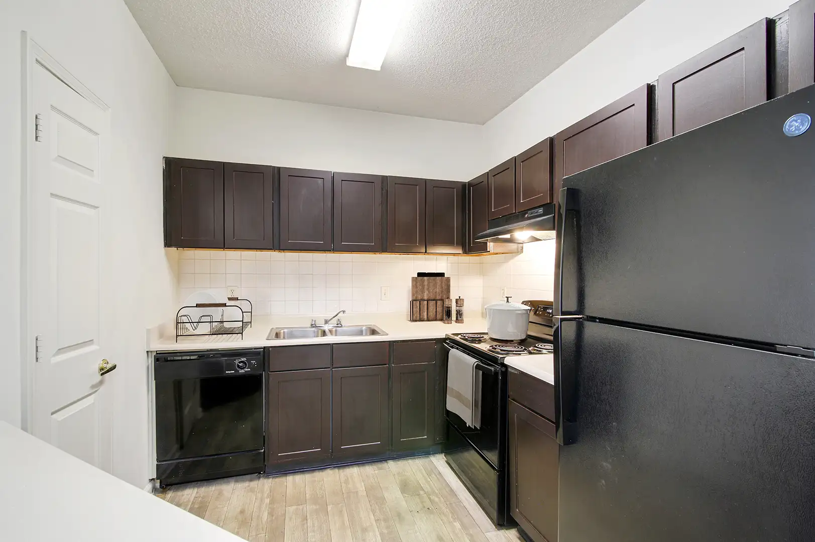 Kitchen with wood-like flooring, espresso cabinetry, and black appliances