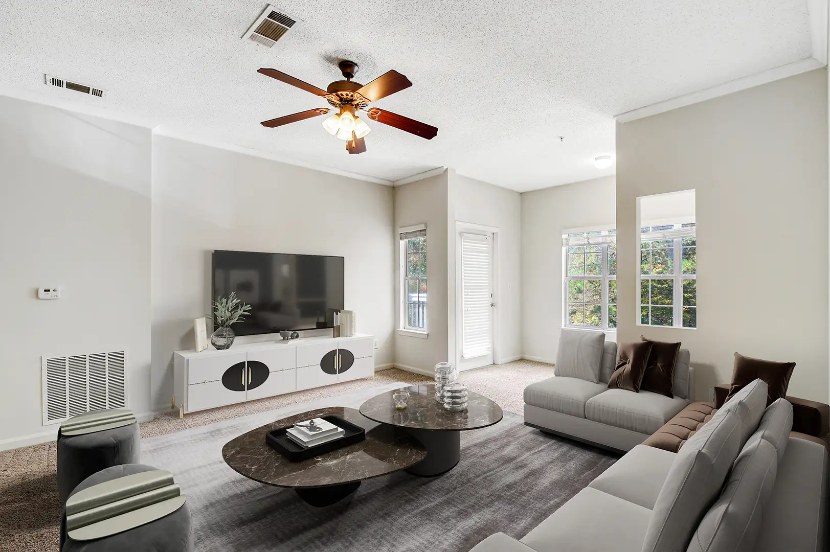 Model living room with large windows and carpeting